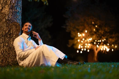 Saudi Man in Thobe Using Smartphone in Night Park