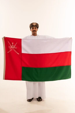 رجل عماني بالزي التقليدي يحمل علم سلطنة عمان