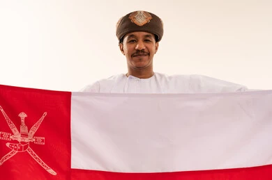 Omani Man in Traditional Dress Holding Oman Flag