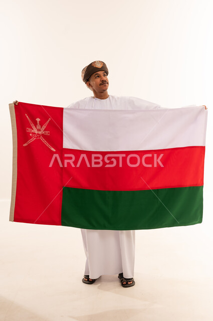 رجل عماني بالزي التقليدي يحمل علم سلطنة عمان