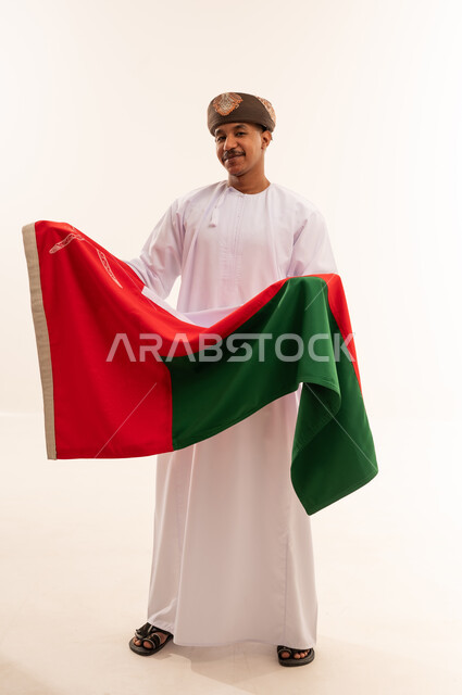 رجل عماني باللباس التقليدي يحمل علم سلطنة عمان