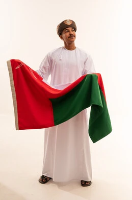 رجل عماني باللباس التقليدي يحمل علم سلطنة عمان