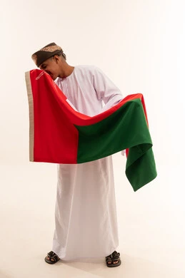 Omani Man in Traditional Dress Kissing Oman Flag