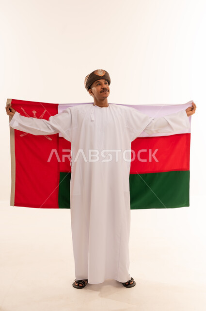 رجل عماني يحمل علم سلطنة عمان بالزي التقليدي