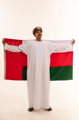 رجل عماني يحمل علم سلطنة عمان بالزي التقليدي