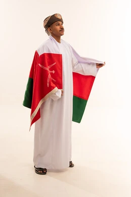 رجل عماني بالزي التقليدي مع علم سلطنة عمان