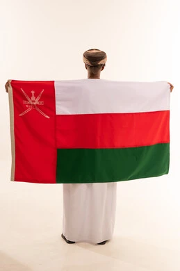 رجل عُماني يحمل علم سلطنة عُمان من الخلف