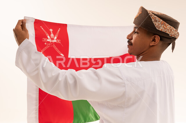 رجل عماني بالزي التقليدي يحمل علم سلطنة عمان