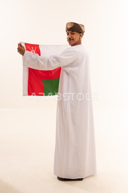رجل عماني بالزي التقليدي يحمل علم سلطنة عمان
