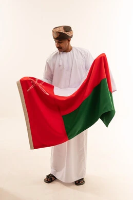 رجل عماني يحمل علم سلطنة عمان في الاستوديو