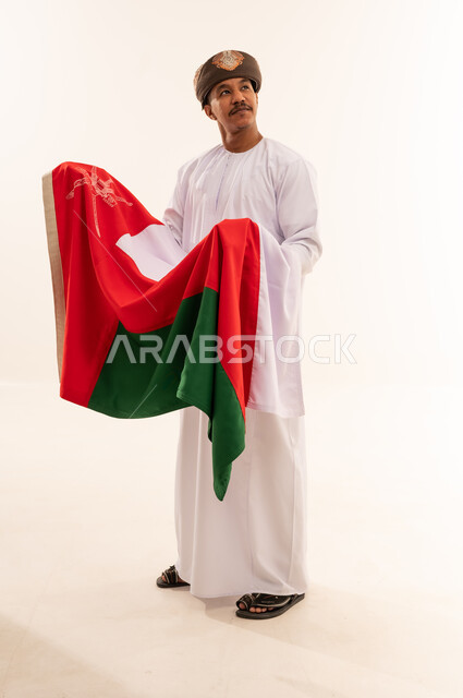 رجل عماني بالزي التقليدي يحمل علم سلطنة عمان