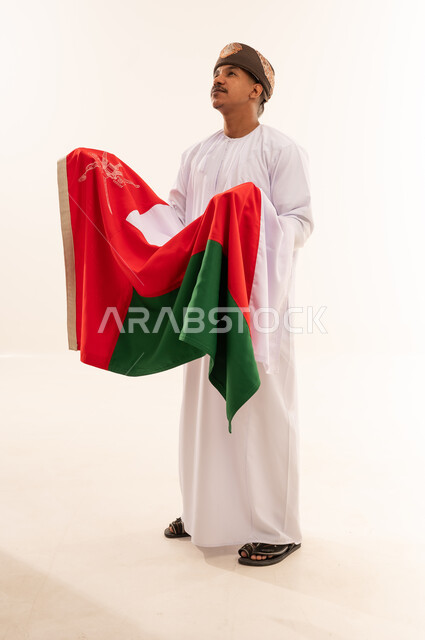 رجل عماني بالزي التقليدي يحمل علم سلطنة عمان