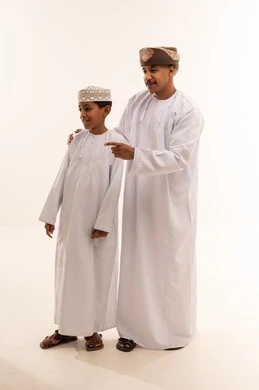 رجل وطفل عُماني بالزي التقليدي يشيران في استوديو