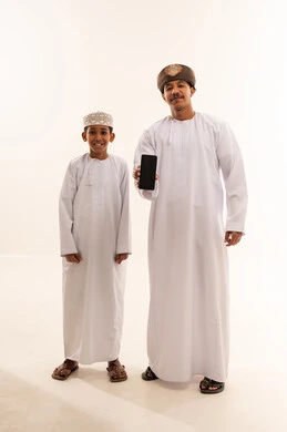 رجل وطفل عماني بالزي التقليدي مع هاتف ذكي