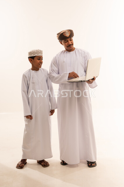 Omani Man and Boy Using Laptop in Traditional Dress