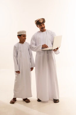 Omani Man and Boy Using Laptop in Traditional Dress