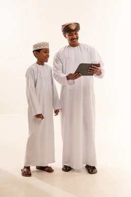 رجل وطفل عمانيان يستخدمان جهازاً لوحياً في الاستوديو