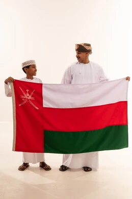 رجل وطفل عمانيان يحملان علم سلطنة عمان