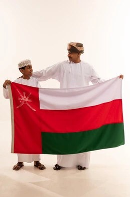 رجل وطفل عماني يحملان علم سلطنة عمان