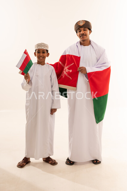 رجل وطفل عماني بالزي التقليدي مع علم عمان