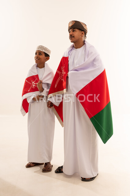 رجل وطفل عماني مع العلم الوطني في الاستوديو