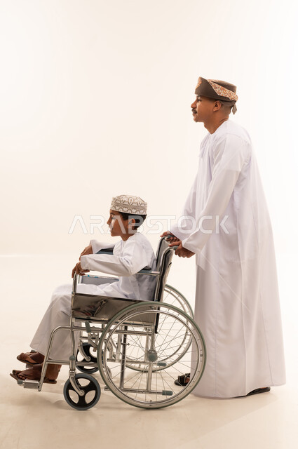 رجل عماني مع طفل على كرسي متحرك خلفية بيضاء