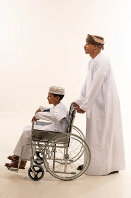 رجل عماني مع طفل على كرسي متحرك خلفية بيضاء