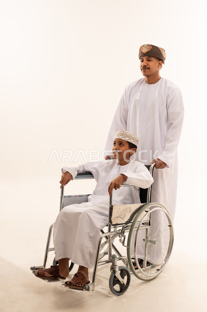 Omani Man Supporting Young Boy in Wheelchair Studio
