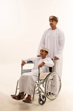 Omani Man Supporting Young Boy in Wheelchair Studio