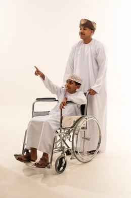 طفل عماني في كرسي متحرك مع والده في الاستوديو