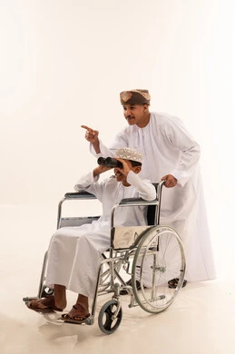 رجل عماني وطفل في كرسي متحرك مع منظار