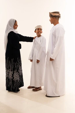 عائلة عُمانية بالزي التقليدي أمام خلفية بيضاء