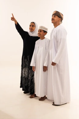 عائلة عمانية بالزي التقليدي ينظرون نحو الأعلى