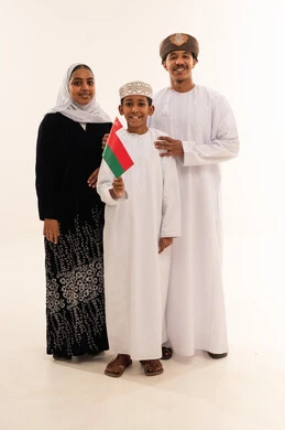 عائلة عمانية بالزي التقليدي تحمل علم عمان