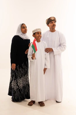 عائلة عمانية بالزي التقليدي يحملون علم عمان