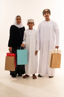 عائلة عُمانية مع حقائب تسوق في الاستوديو