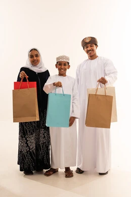 عائلة عمانية بالزي التقليدي مع حقائب تسوق