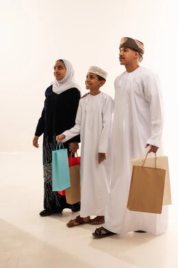عائلة عمانية تحمل حقائب تسوق بالزي العماني التقليدي