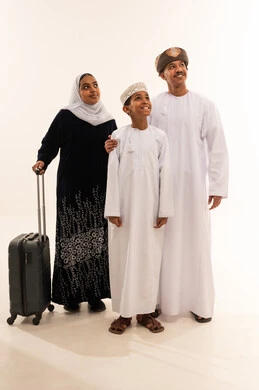 عائلة عمانية مع حقيبة سفر على خلفية بيضاء