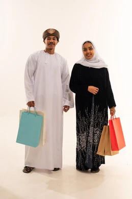 رجل وامرأة عُمانيان بملابس تقليدية وحقائب تسوق