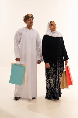 زوجين عمانيين مع حقائب تسوق على خلفية بيضاء