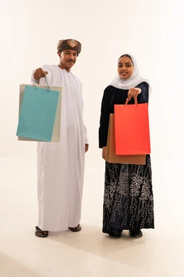 زوجان عمانيان بالزي التقليدي يحملان أكياس تسوق
