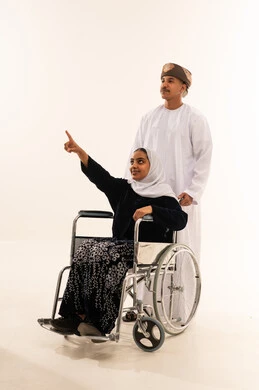 امرأة عمانية على كرسي متحرك مع رجل بالزي التقليدي