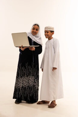 امرأة وطفل عُمانيان مع جهاز كمبيوتر محمول