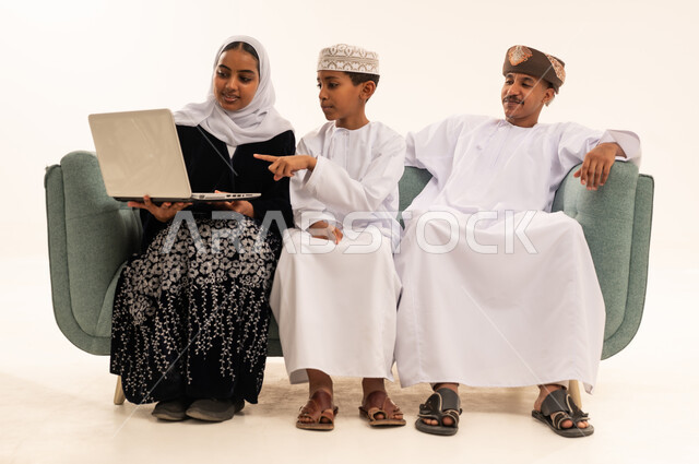 عائلة عمانية تستخدم الحاسوب المحمول بالزي التقليدي