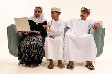 عائلة عمانية تستخدم الحاسوب المحمول بالزي التقليدي
