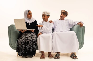 Omani Family Using Laptop on Sofa White Background