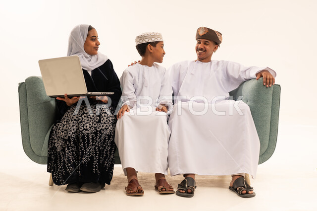 عائلة عمانية تستخدم الحاسوب المحمول على الأريكة