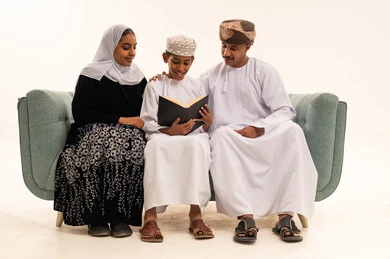 Omani Family in Traditional Attire Reading Book