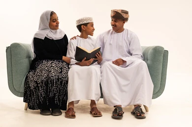 عائلة عمانية تقرأ كتاب بالملابس التقليدية